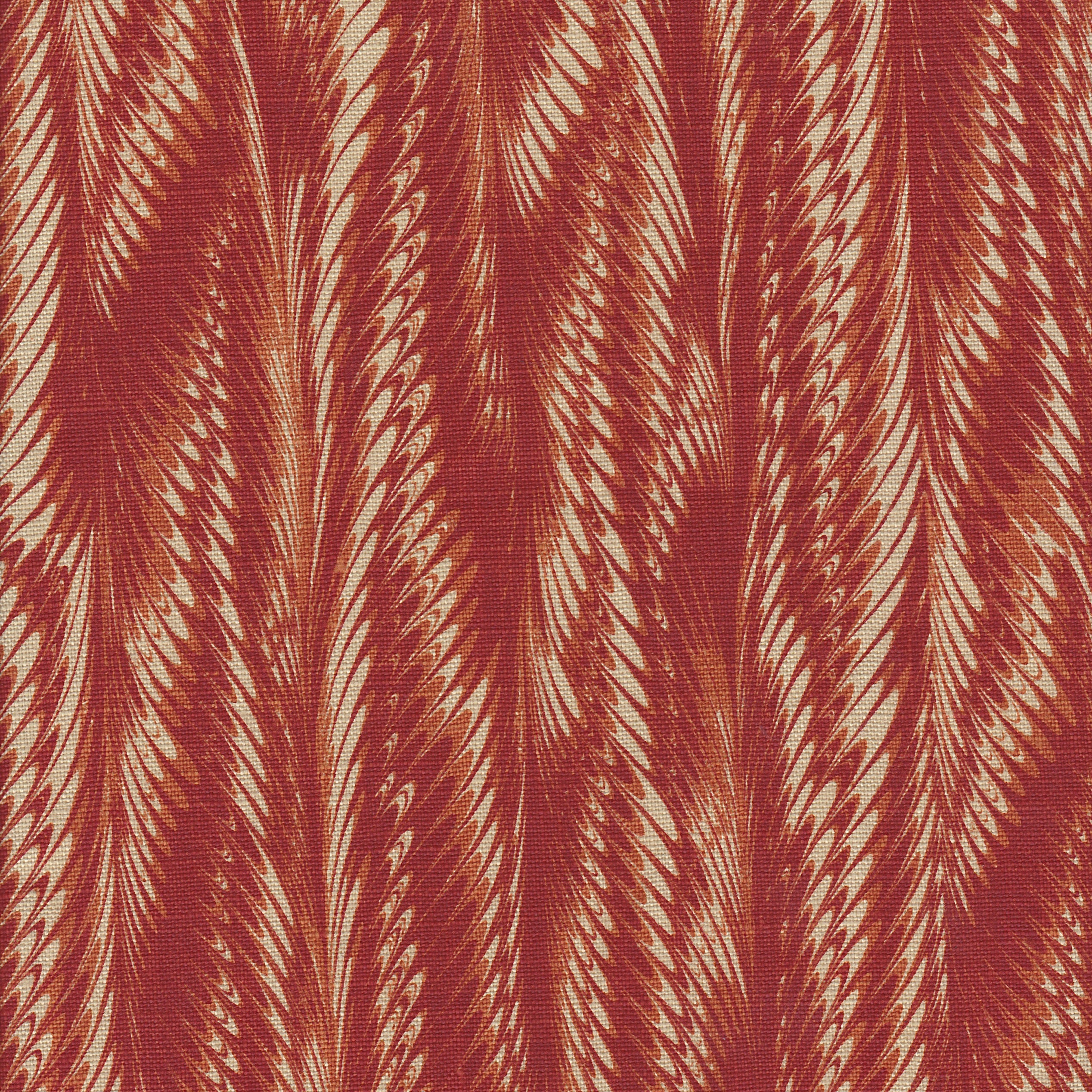 Detail of fabric in a marbled paint print in shades of red, orange and tan.