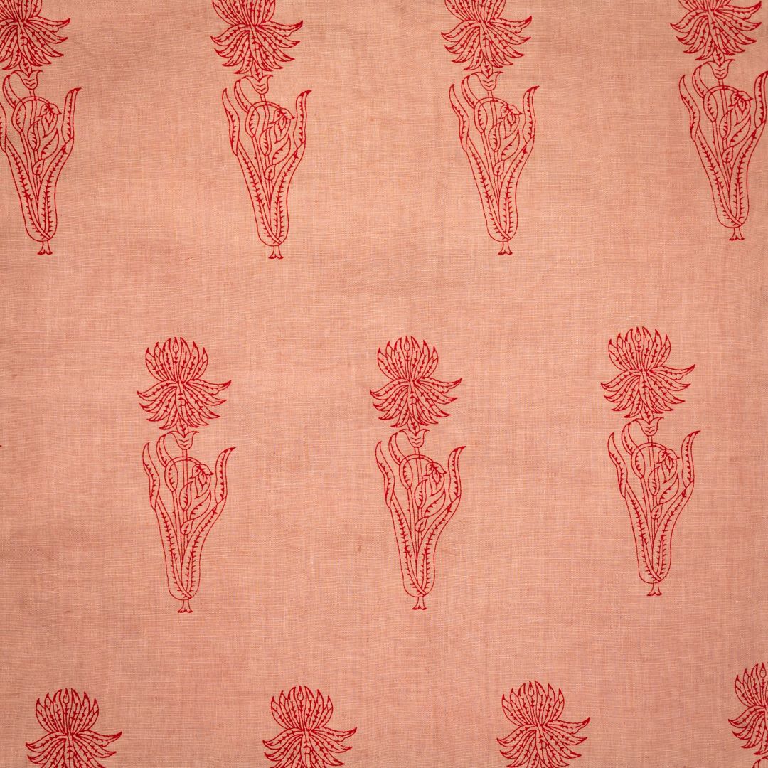 Detail of fabric in a floral grid print in red on a light orange field.