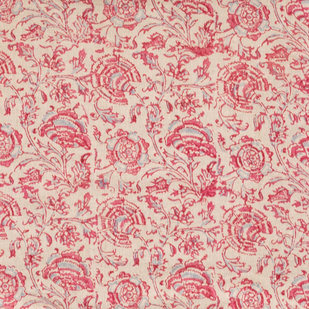Detail of fabric in a dense botanical print in pink and blue on a cream field.