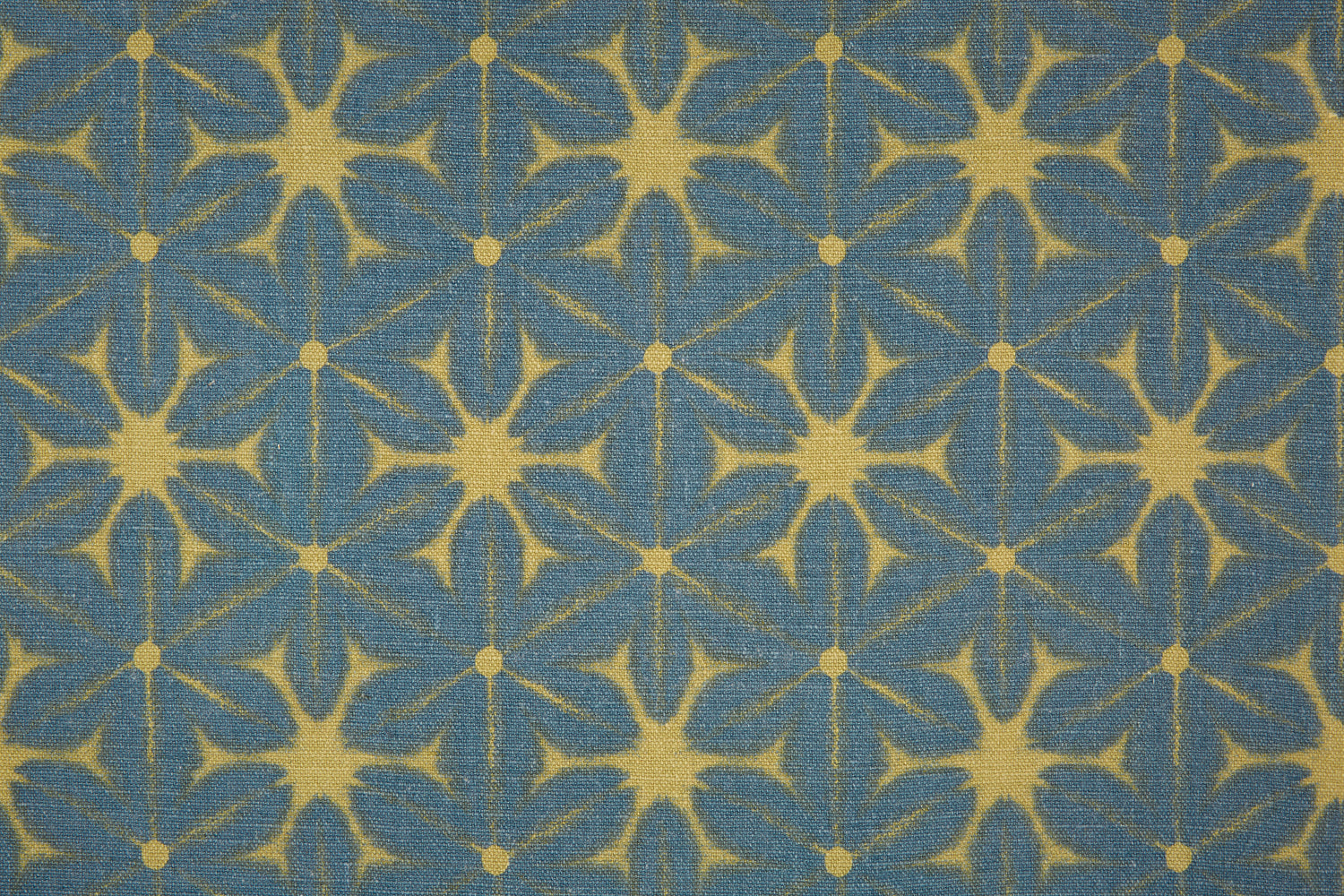 Detail of fabric in a shibori grid print in mustard on a navy field.