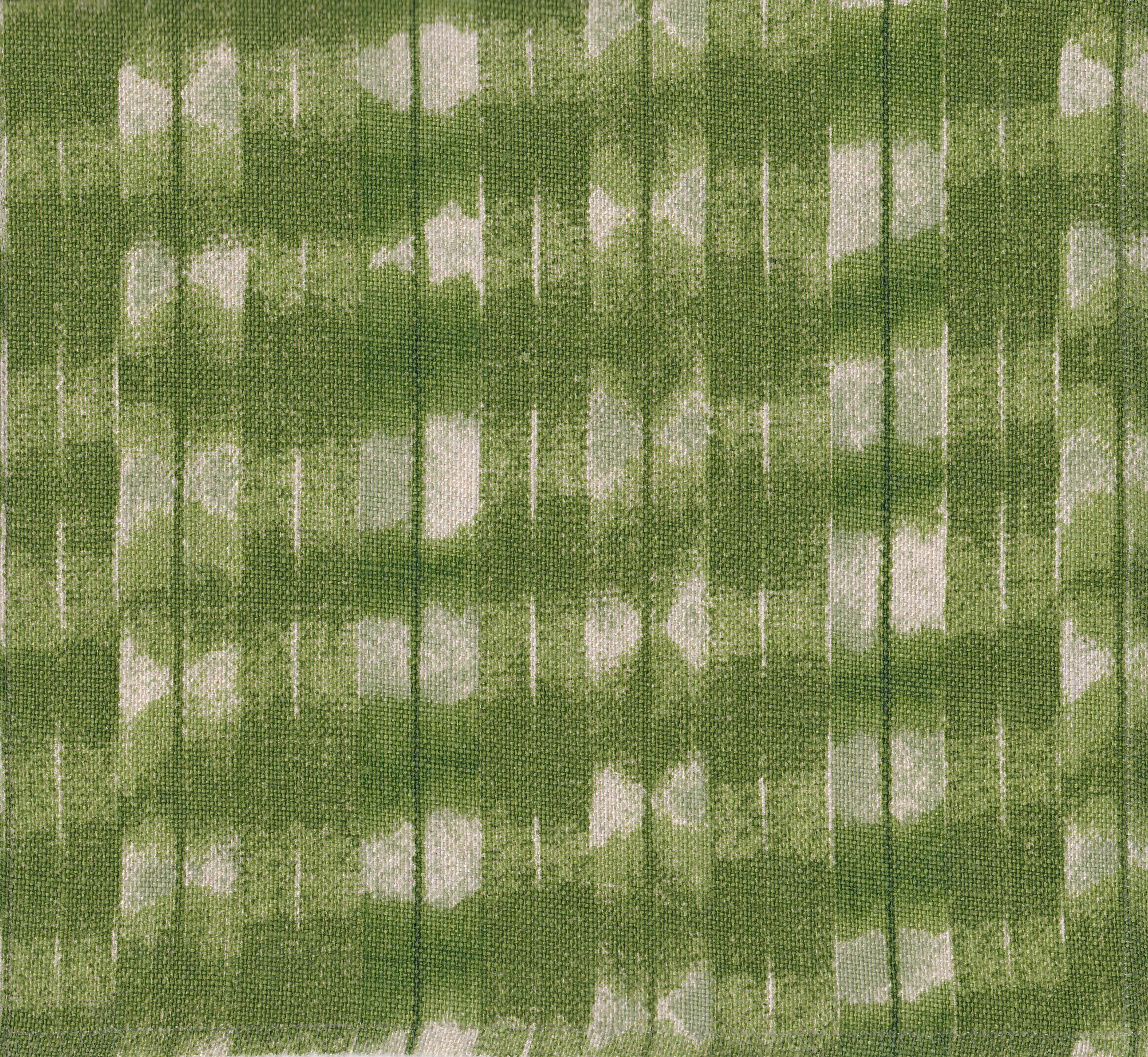 Detail of fabric in a textural shibori print in shades of green on a greige field.