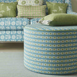 An ottoman and sofa covered in throw pillows, both upholstered in coordinating blue and green printed fabrics.