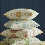 A stack of throw pillows in different colorways of the same playful berry and leaf print.