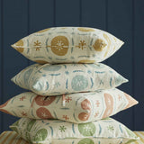 A stack of throw pillows in different colorways of the same playful berry and leaf print.