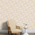 Armchair and end table in front of a wall papered in a floral print in yellow, green and light pink.