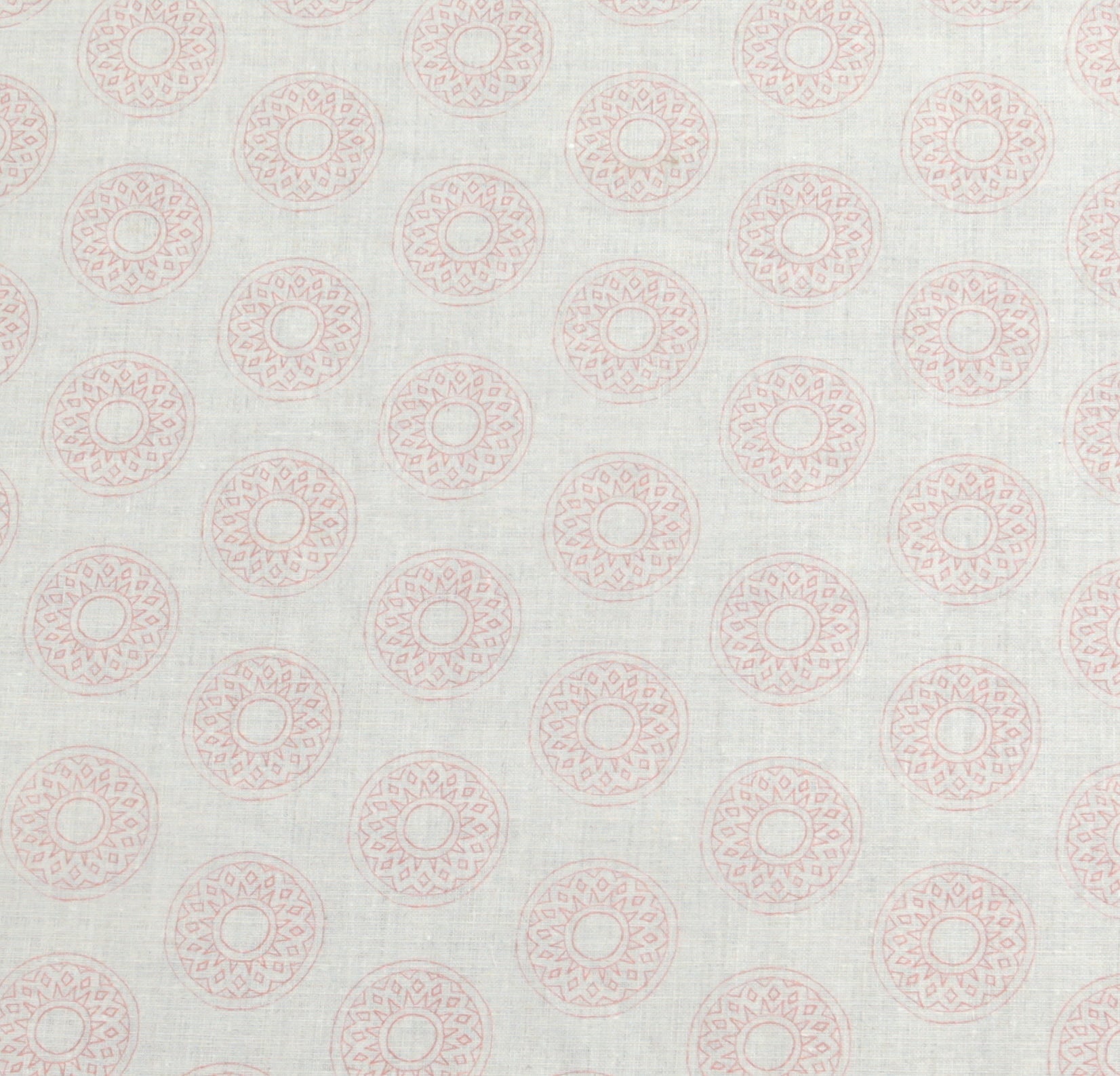 Detail of fabric in a repeating circular geometric print in light pink on a greige field.