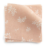 A stack of fabric swatches in a minimal repeating leaf print in cream on a light pink field.