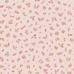 Detail of fabric in a minimal repeating leaf print in red on a light pink field.