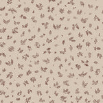 Detail of fabric in a minimal repeating leaf print in brown on a tan field.