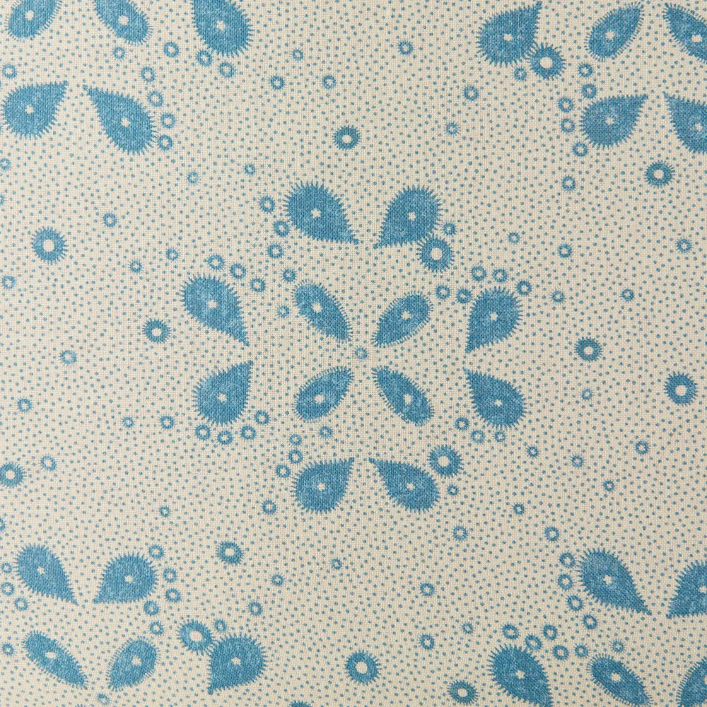 Detail of fabric in a playful paisley print in blue on a tan field.