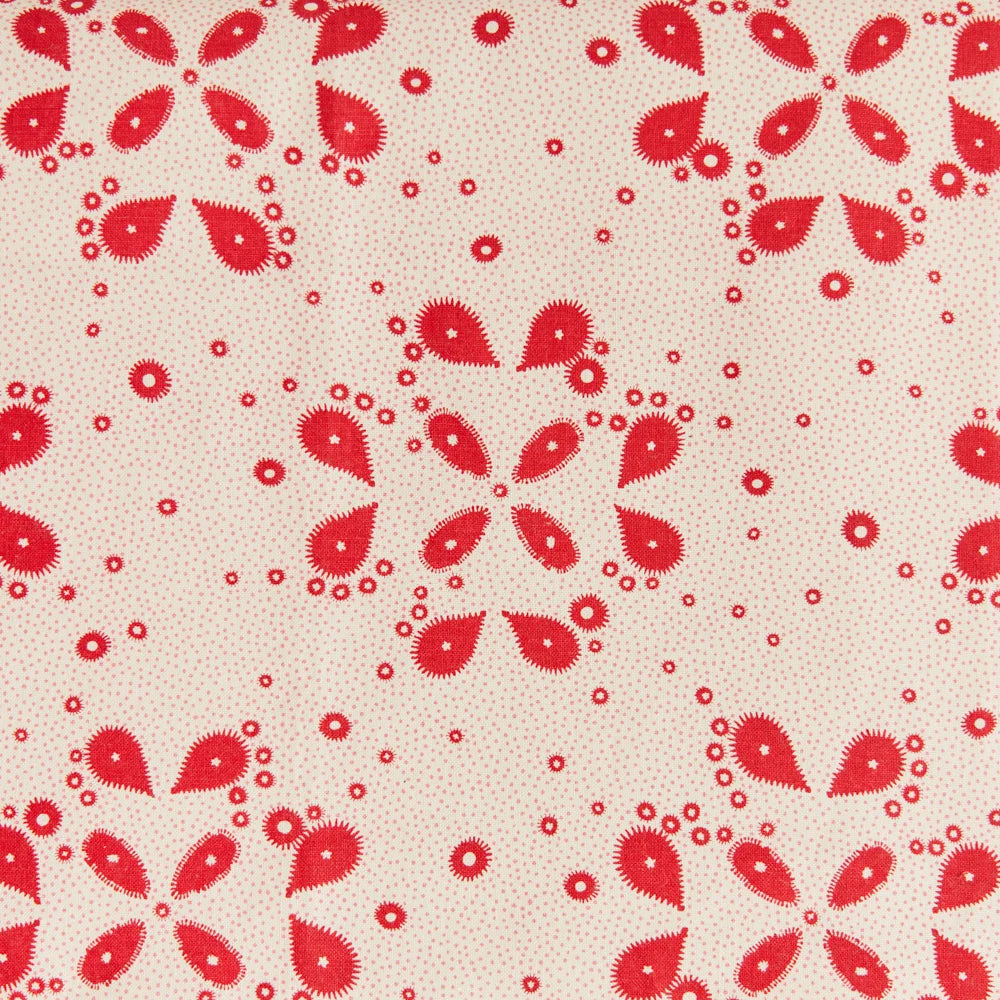 Detail of fabric in a playful paisley print in red on a tan field.