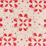 Detail of fabric in a playful paisley print in red on a tan field.