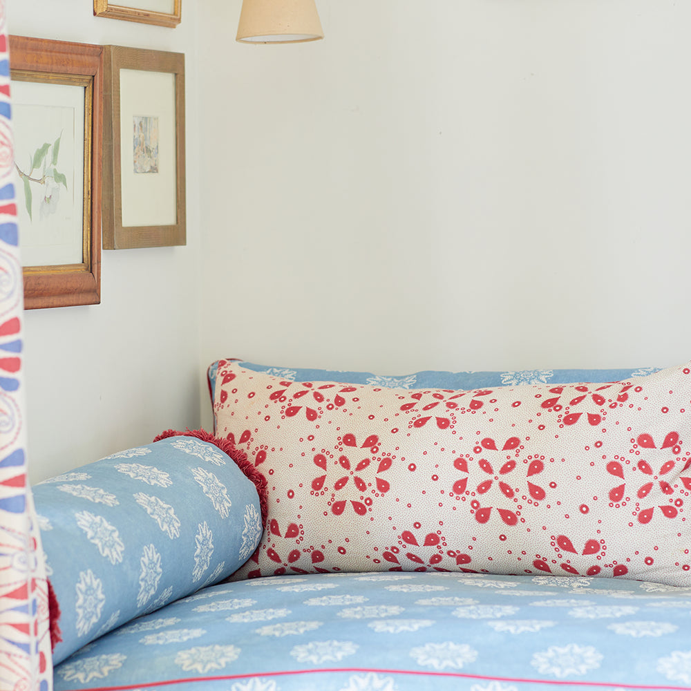 An upholstered couch topped in a throw pillow, both in floral prints in different colorways.