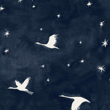 Detail of fabric in a repeating print of birds and stars in white on a navy watercolor field.