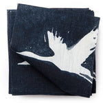 A stack of fabric swatches in a repeating print of birds and stars in white on a navy watercolor field.