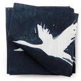 A stack of fabric swatches in a repeating print of birds and stars in white on a navy watercolor field.