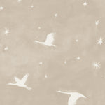 Detail of fabric in a repeating print of birds and stars in white on a cream watercolor field.