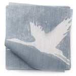 A stack of fabric swatches in a repeating print of birds and stars in white on a blue-gray watercolor field.