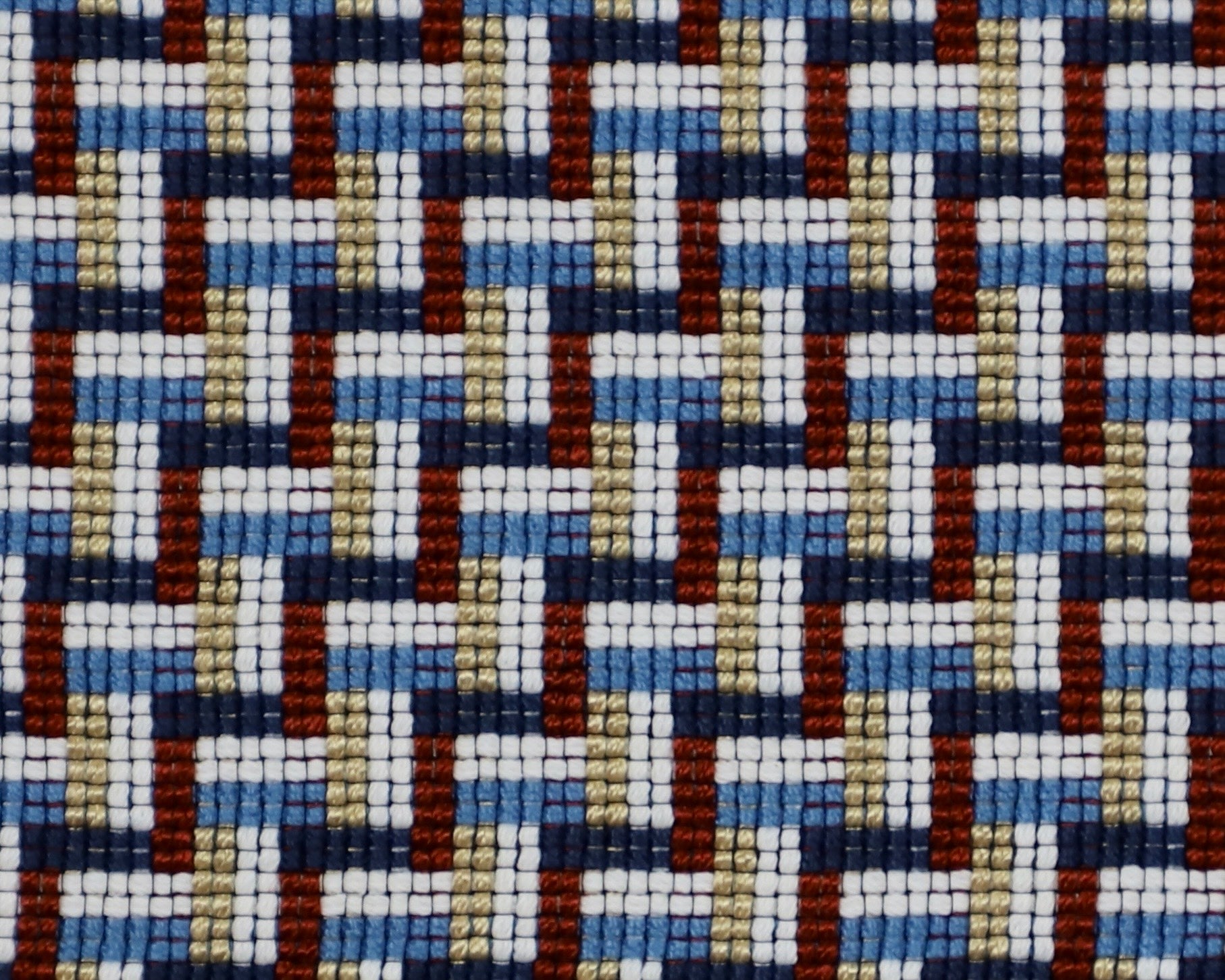 Detail of a woven stair step pattern in navy blue, white, red and gold.