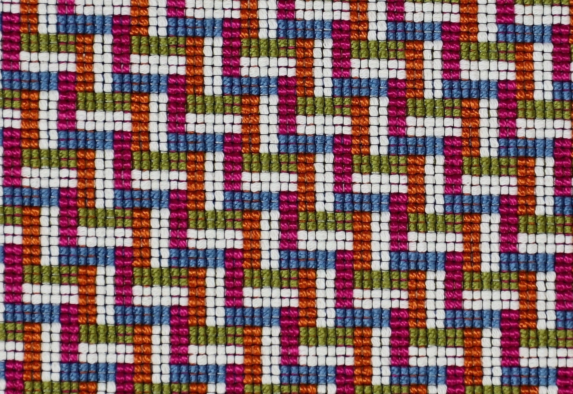 Detail of a woven stair step pattern in hot pink, chambray, orange, white and lime green.