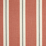 Detail of fabric in a repeating stripe print in white and gray on a burnt orange field.