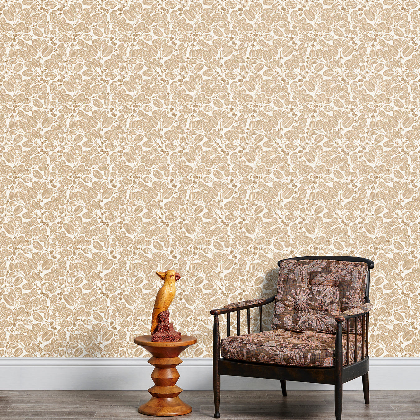 Armchair and end table in front of a wall papered in a dense leaf and stem print in brown and white.