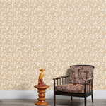 Armchair and end table in front of a wall papered in a dense leaf and stem print in brown and white.