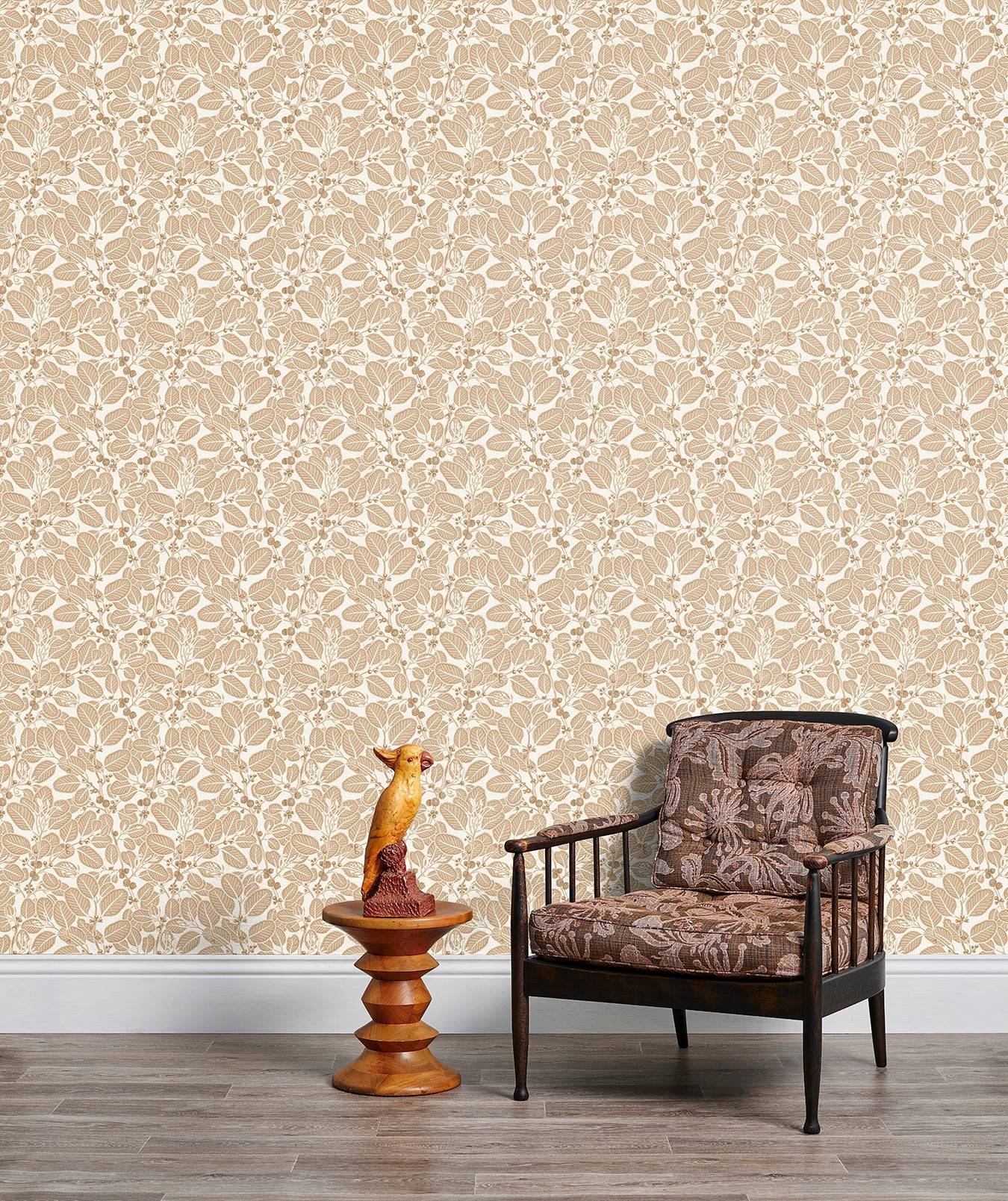 Armchair and end table in front of a wall papered in a dense leaf and stem print in brown and white.