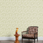 Armchair and end table in front of a wall papered in a dense leaf and stem print in sage and white.