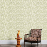 Armchair and end table in front of a wall papered in a dense leaf and stem print in sage and white.