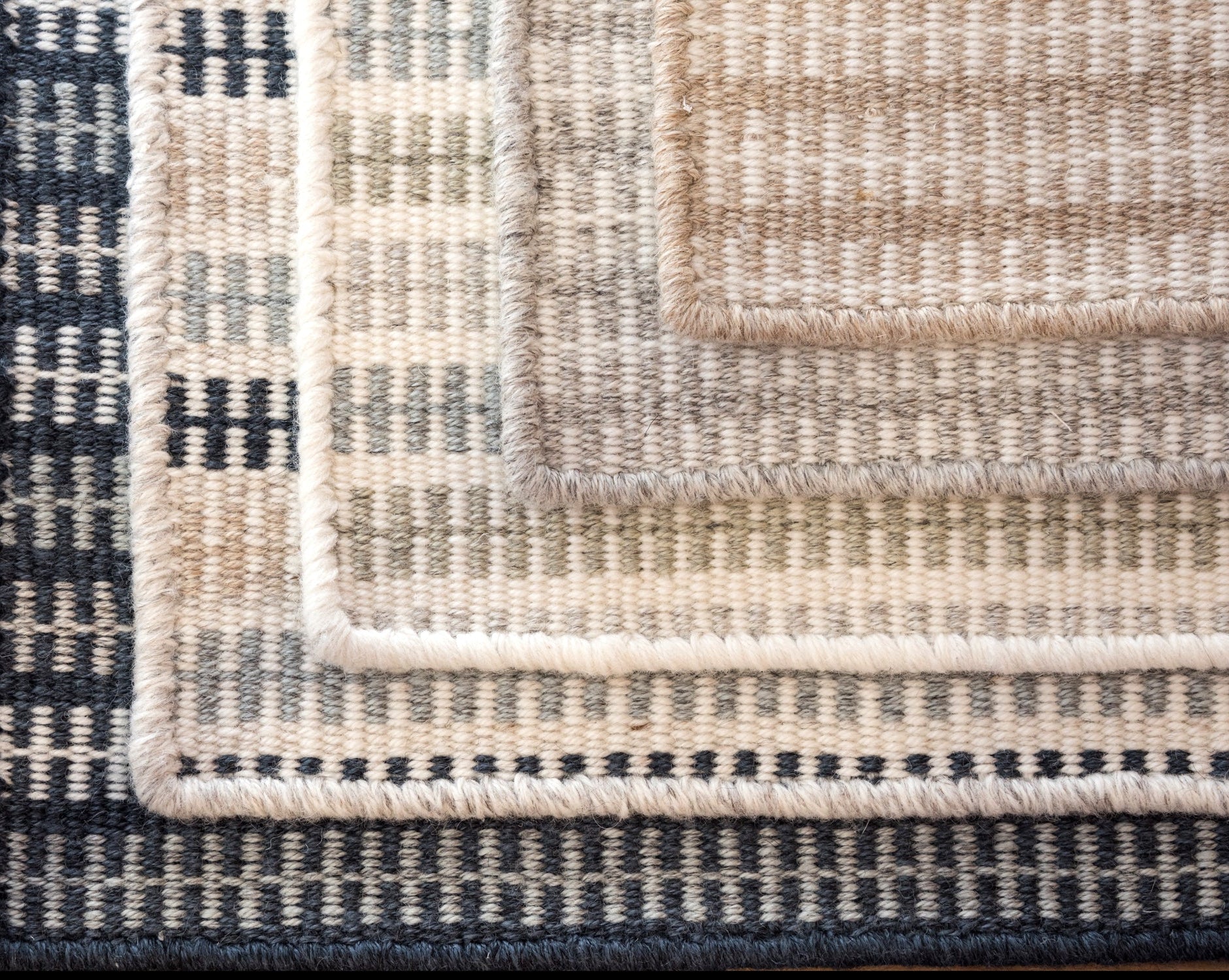 Stack of broadloom carpet samples in a ticking stripe pattern in an array of colors. 
