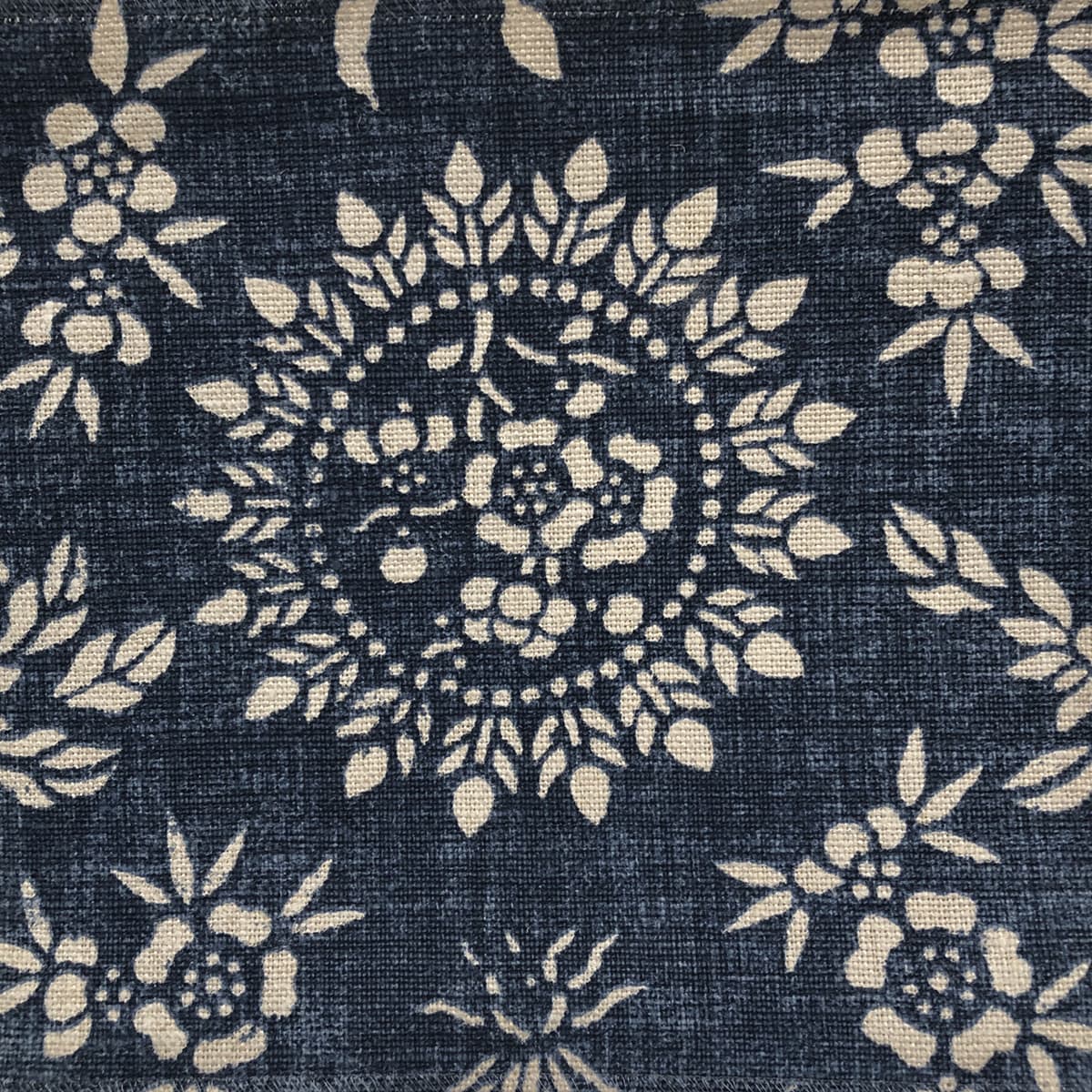 Detail of fabric in a geometric floral print in cream on an indigo field.