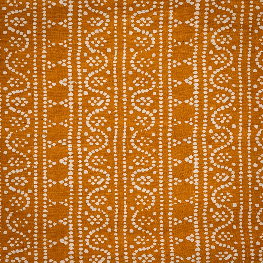 Detail of fabric in a dotted geometric stripe in cream on an ochre field.