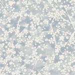 Detail of fabric in a painterly branch print in white on a blue-gray watercolor field.