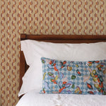 Bed with patterned headboard, floral pillow, and books on a brown striped wallpaper.