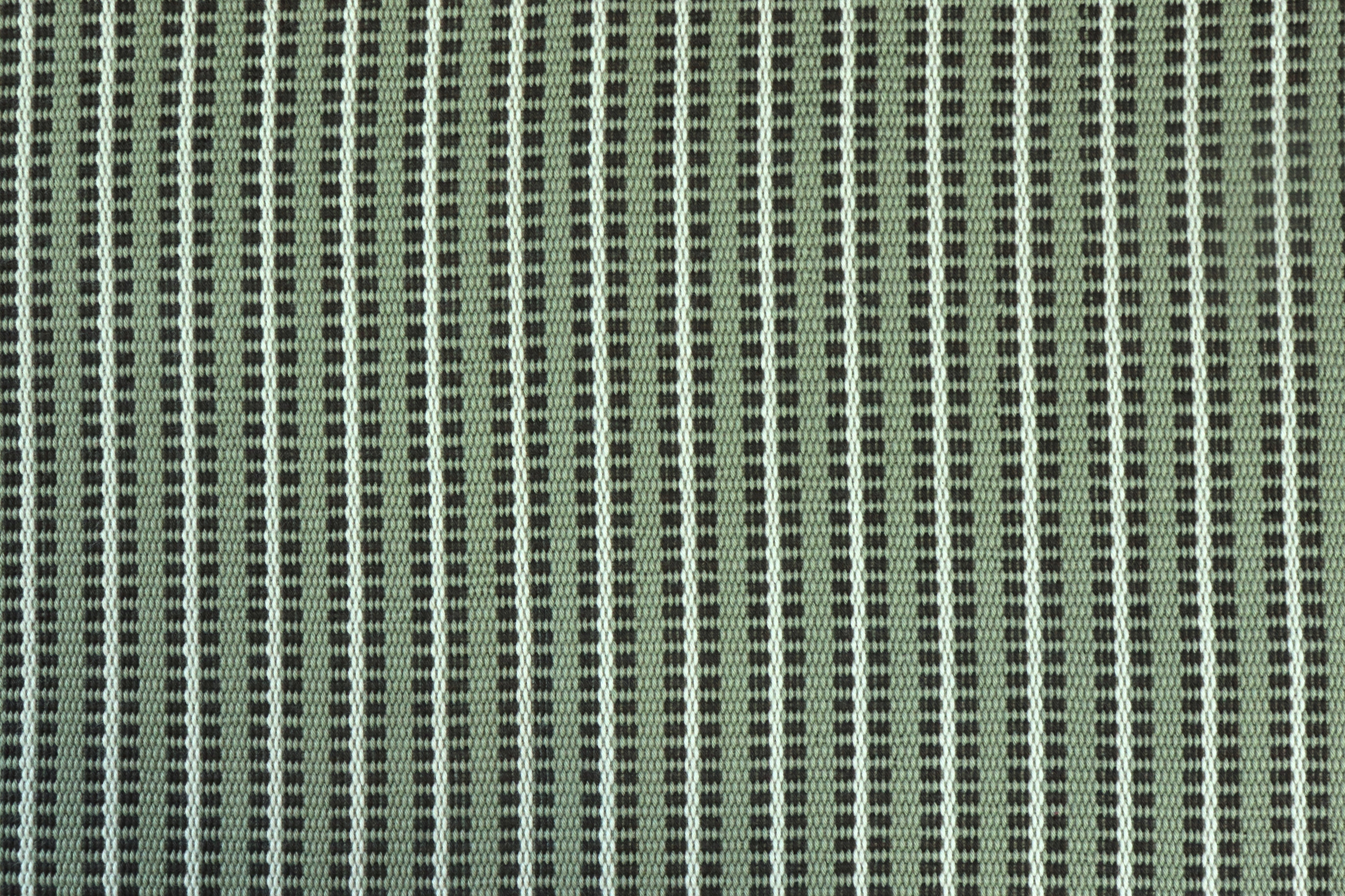 Close-up of a textured green fabric with a subtle stripe pattern