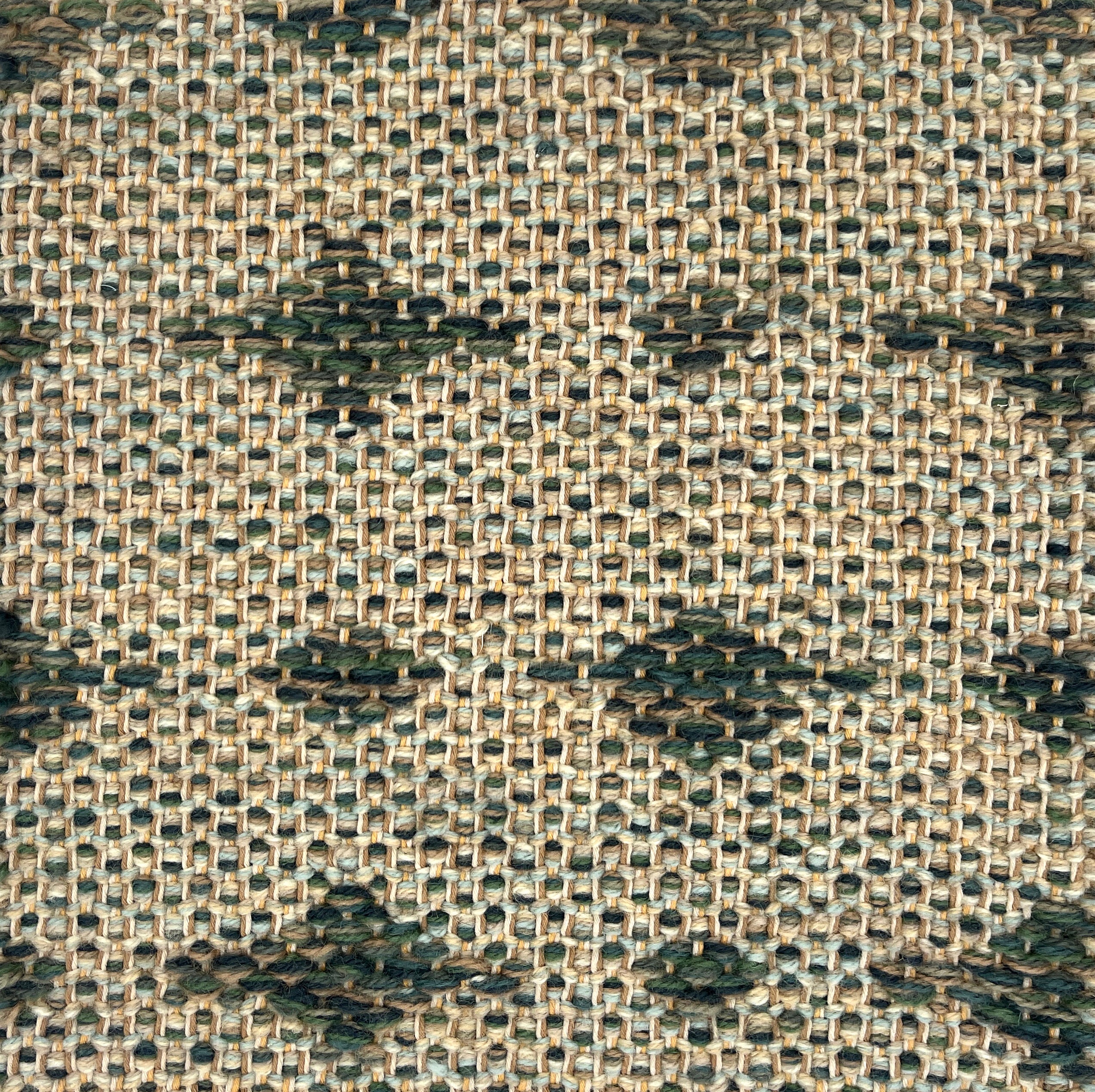Close-up of a woven rug  with a diamond pattern in shades of green.