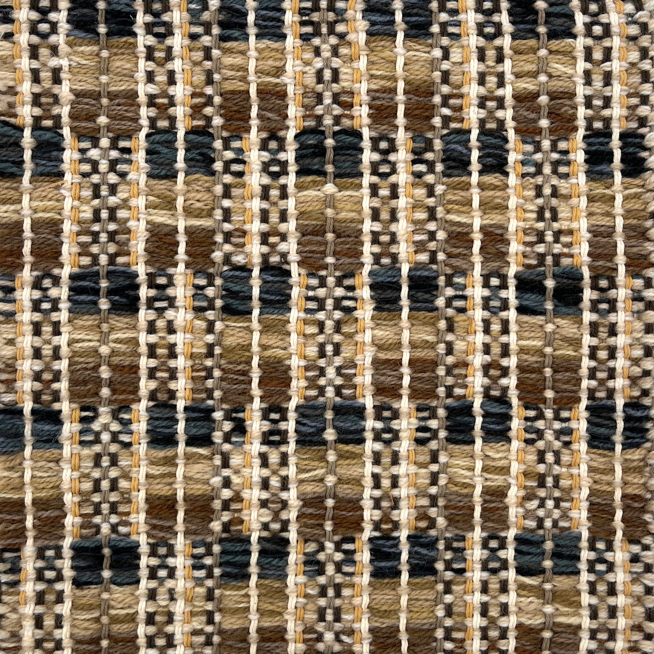 Close-up of a woven rug  with a geometric checker pattern in tan, brown  and blue.