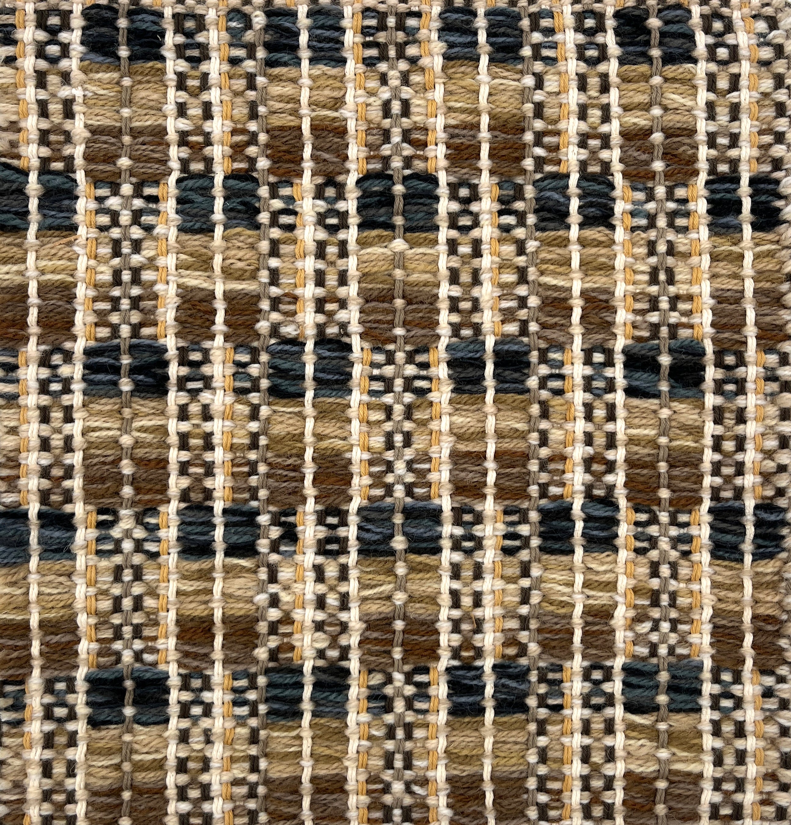 Close-up of a woven rug  with a geometric checker pattern in tan, brown  and blue.