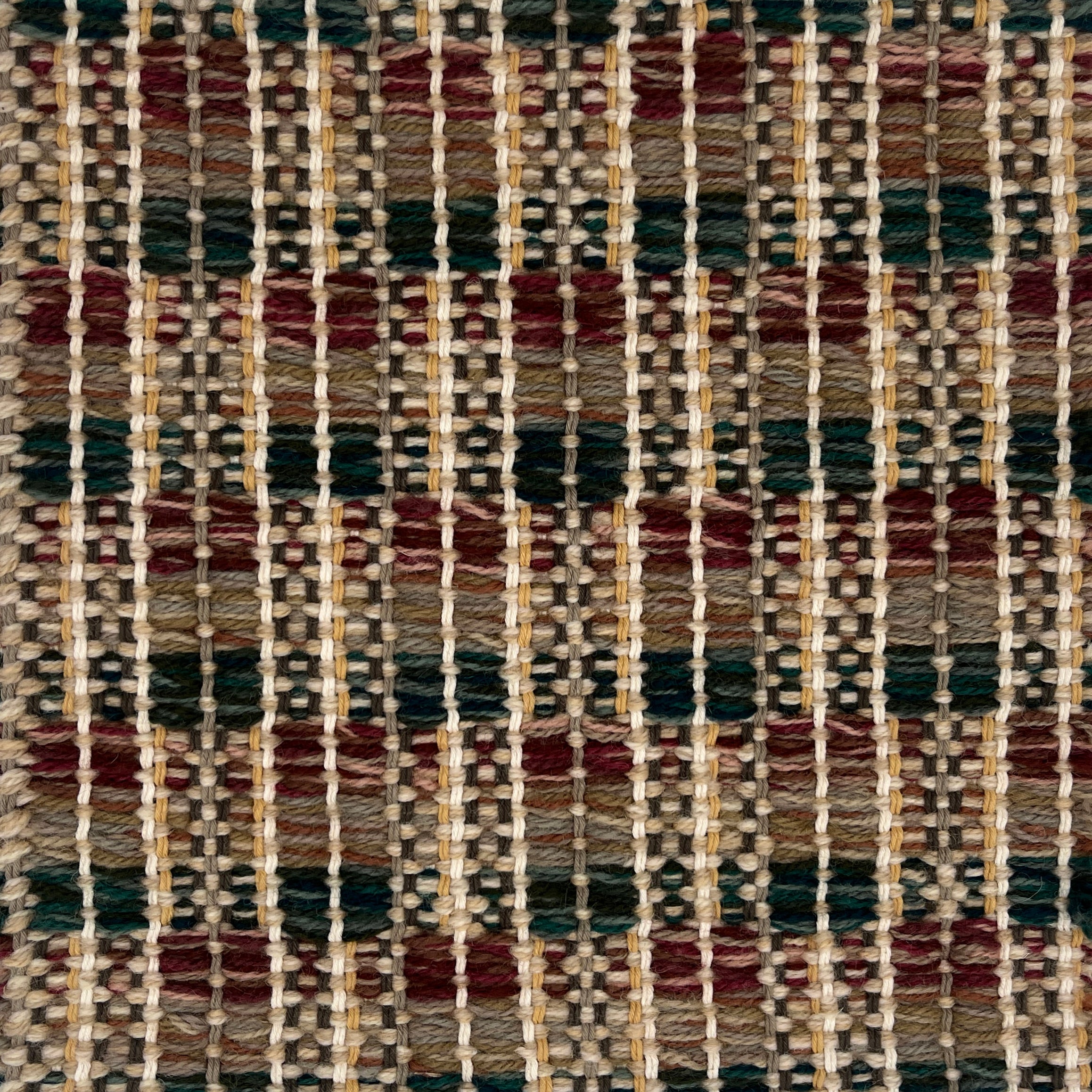 Close-up of a woven rug  with a geometric checker pattern in brown, green and brick red.