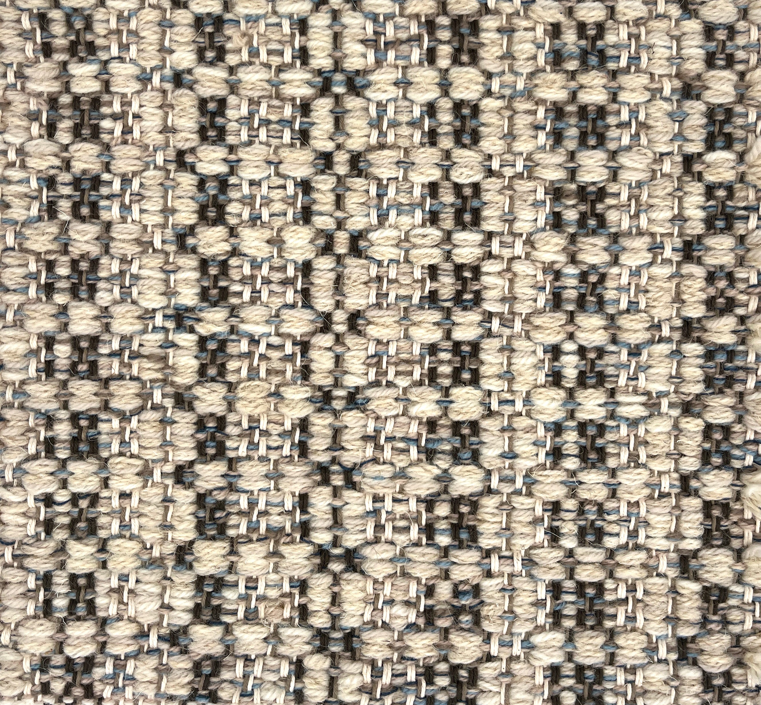 Close-up of a woven rug with textural pattern in shades of grey.