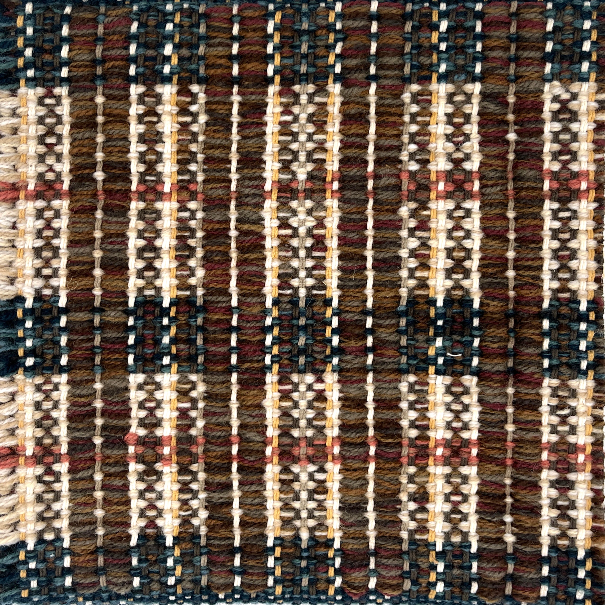 Close-up of a woven rug  with a plaid pattern in brown, beige, and teal.