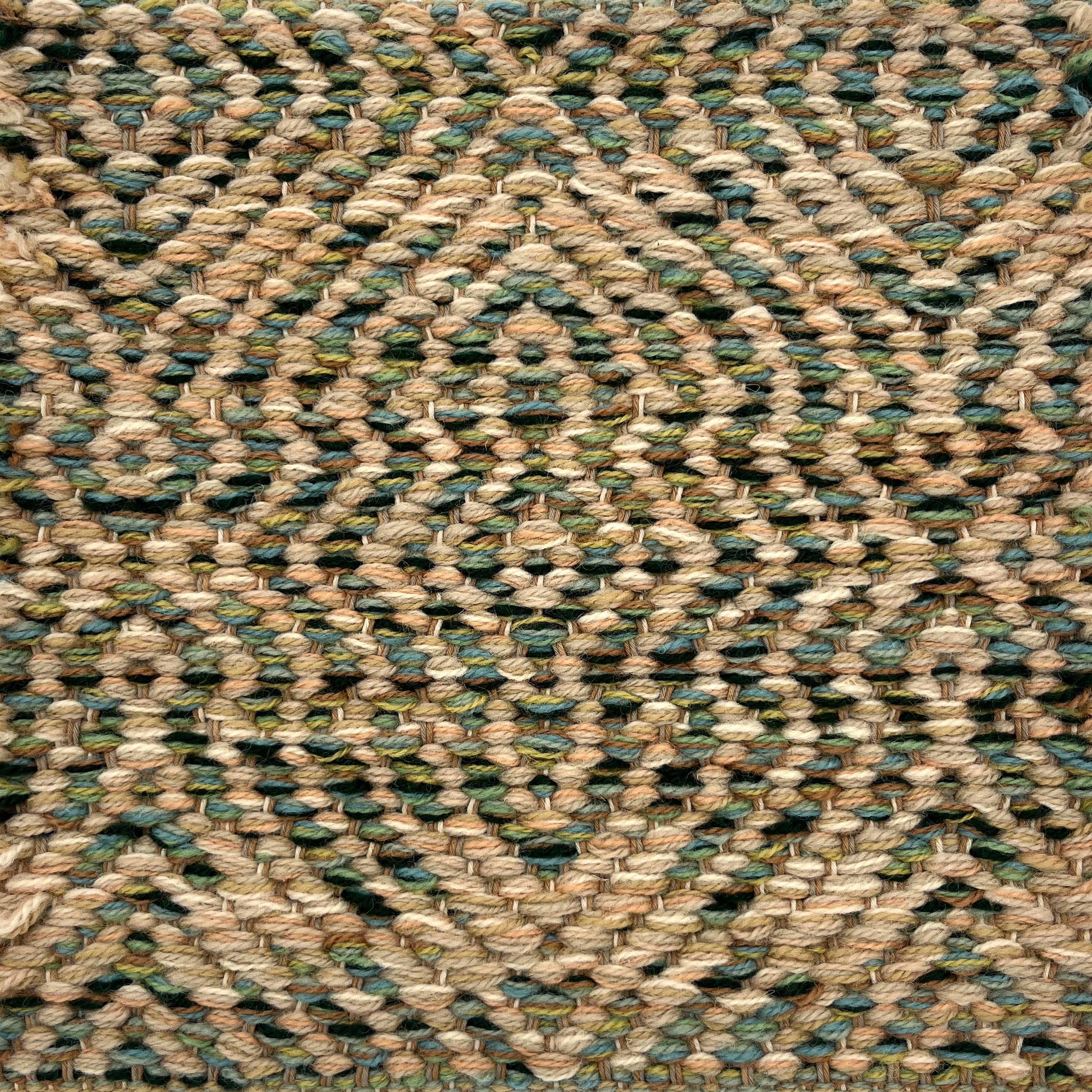 Textured handwoven rug with a diamond pattern in tan and green.