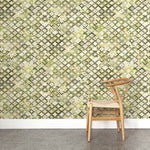 A wooden chair stands in front of a wall papered in a painterly small-scale diamond print in cream, green and gray.