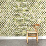 A wooden chair stands in front of a wall papered in a painterly small-scale diamond print in cream, green and gray.