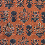 Detail of fabric in a repeating vase and plant print in navy on a mottled rust field.