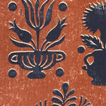 Close-up of fabric in a repeating vase and plant print in navy on a mottled rust field.