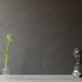 A table with knick knacks stands in front of a wall papered in mottled gray and black.