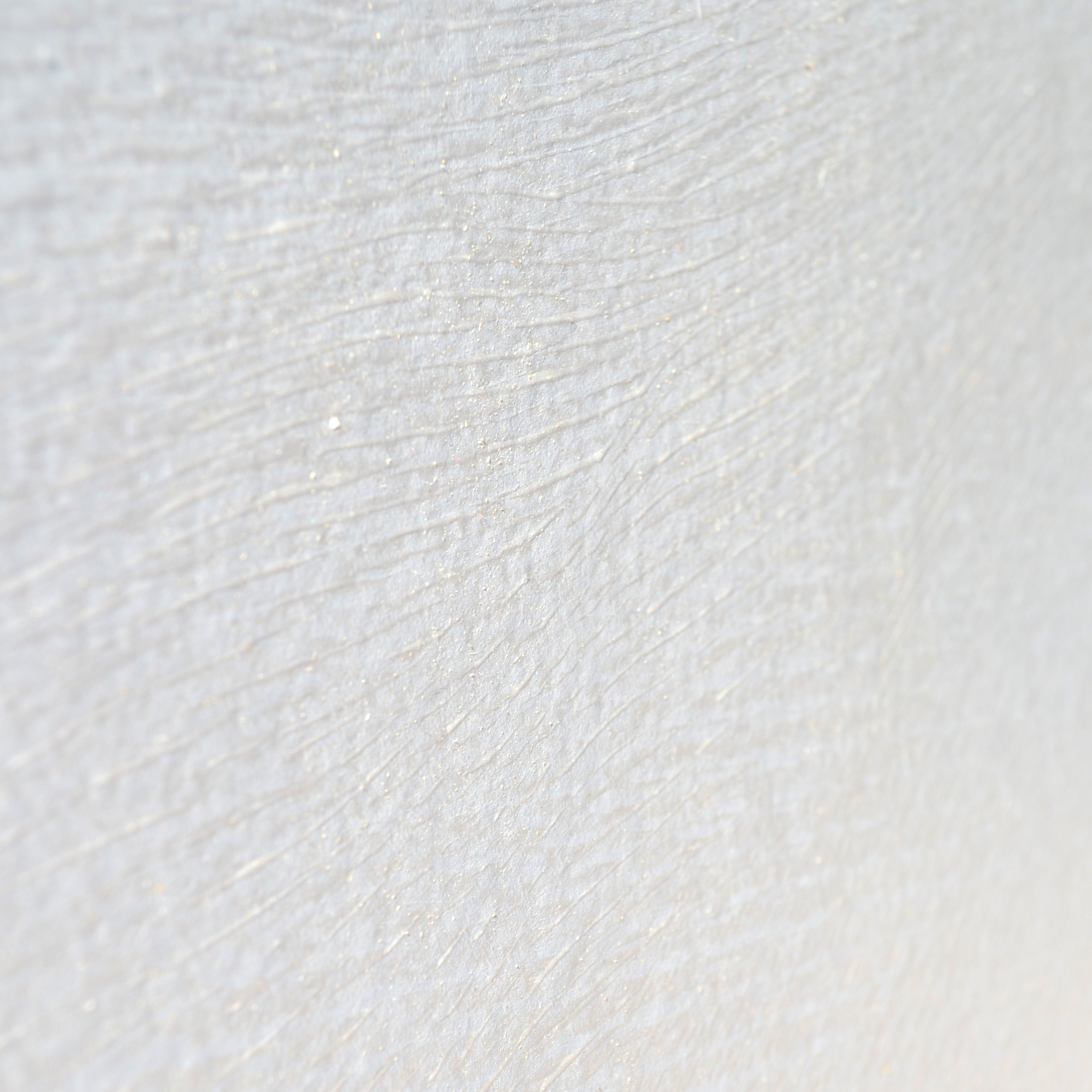 Detail of a wallpaper in an abstract ridged texture in metallic pearl.