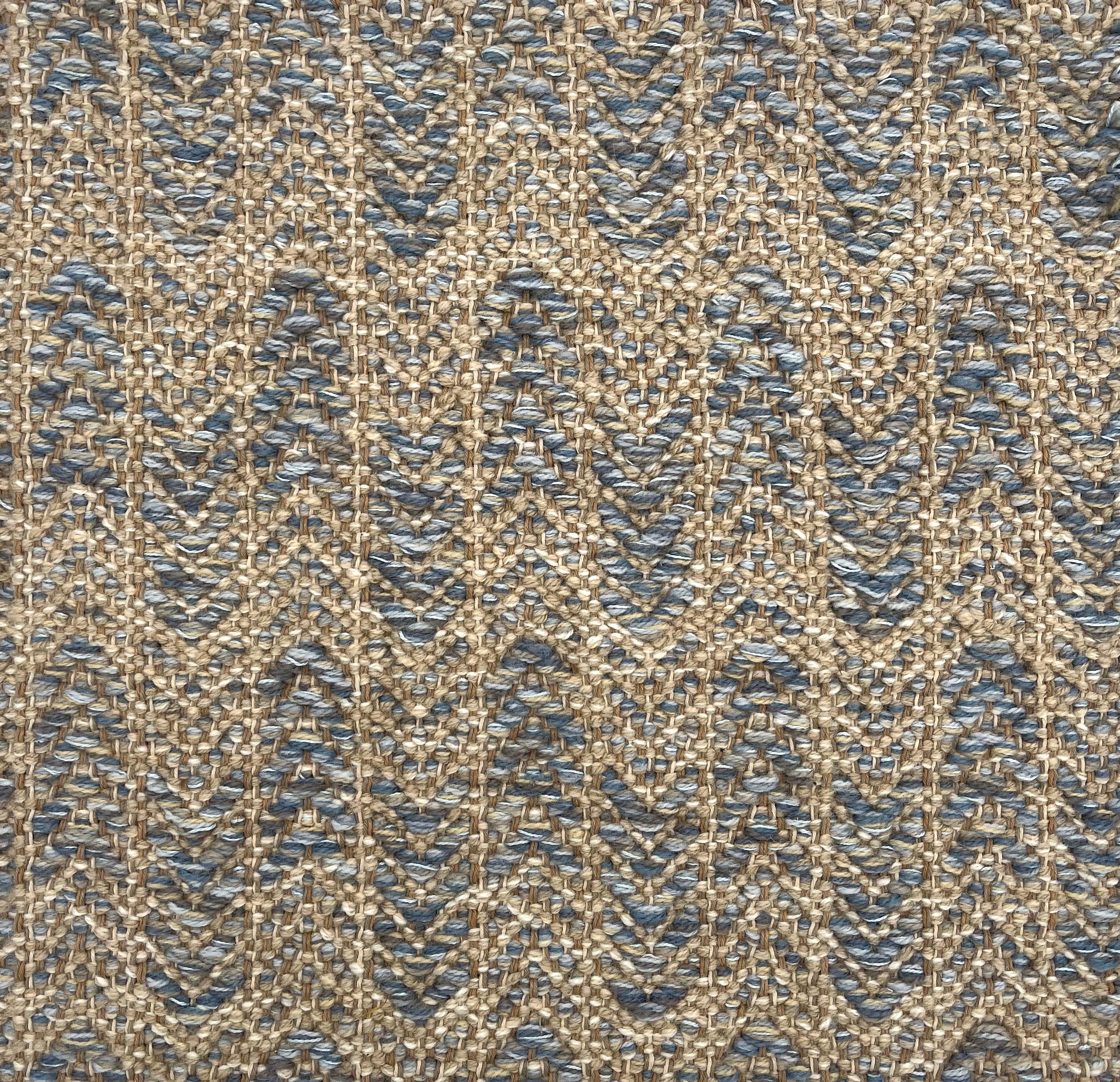 Handwoven rug detail in a herringbone design in blue and tan